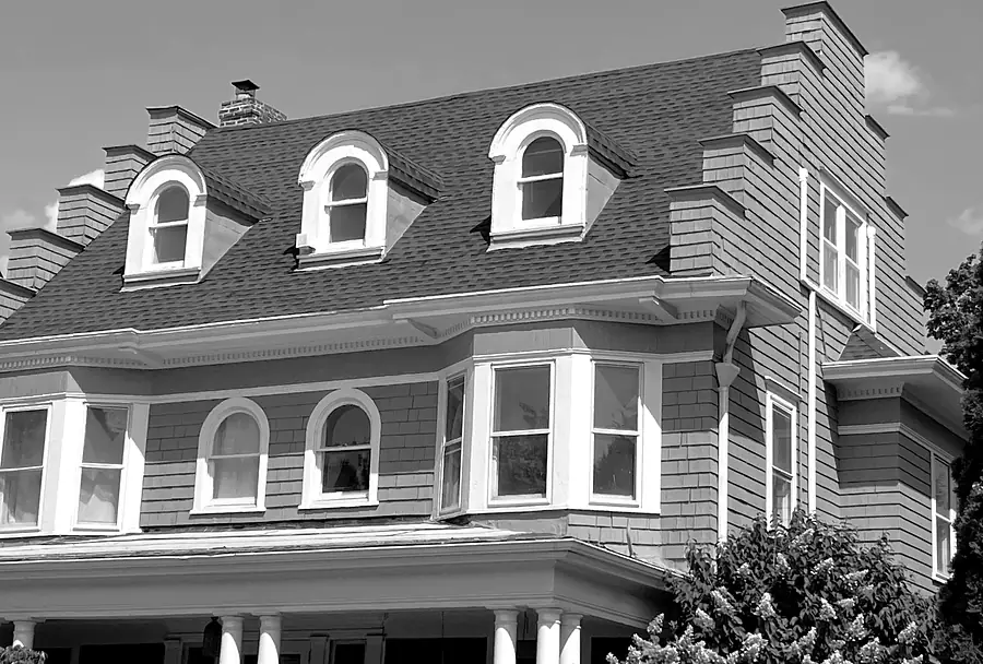 Gray-shingled Victorian-style house with arched dormer windows and a front porch